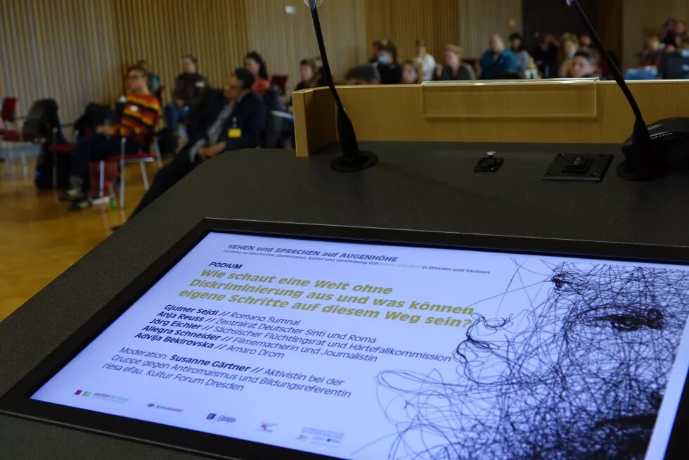 Blick auf den Screen am Redner*innenpult. Hier wird das Podium angekündigt.