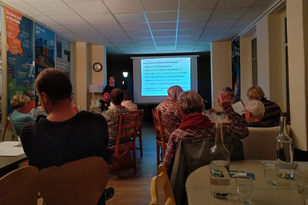 Blick durch den Saal nach vorn, wo gerade die Auflösung der Wasserverkostung stattfindet