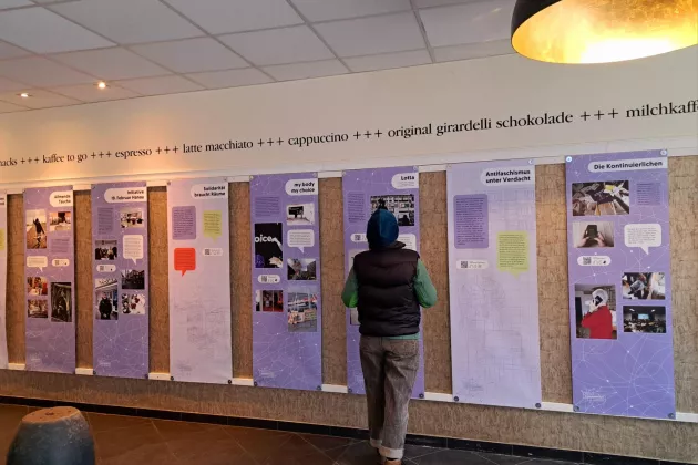 Eine Person steht vor den Bannern aus der Ausstellung 