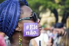 Eine Schwarze Frau protestiert gegen Jair Bolsonaro. Sie hat einen Sticker auf ihre Wange geklebt, auf dem steht "ele não", das bedeutet "Er nicht".