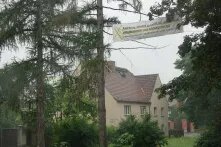 Zwischen zwei Bäumen mitten im historischen Dorfkern Pödelwitz hängt ein Transparent mit der Aufschrift: Pödelwitz - Unsere Zukunft ist solidarisch, selbstbestimmt und klimagerecht.