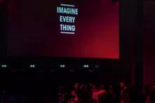 Schwarz rote Töne. Auf einer Kinileinwand ist zu lesen Imagine everything