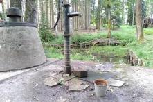 In der Bildmitte ist eine historische Pumpe zu sehen, die Wasser aus der Tiefe nach oben befördert.