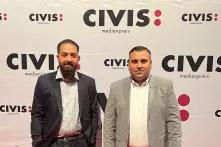 Die Podcaster Sejnur Memisi und Nino Novakovic stehen vor einem Banner des CIVIS Medienpreises, für den sie im Jahr 2022 nominiert sind.