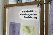 Mit Gummis werden die Banner durch Ösen in die Holzrahmen gespannt.