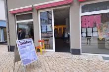 Das Haus ZundA mit offener Tür. Im Raum hängen Banner der Ausstellung "zusammentun". Vor der Tür steht ein Plakataufsteller und weist auf die Veranstaltung hin.