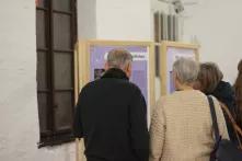 drei Menschen schauen ein Ausstellungsbanner an, sie sind von hinten zu sehen.