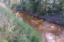 Blick auf den braunen Flutgraben zwischen Mulkwitz und Mühlrose