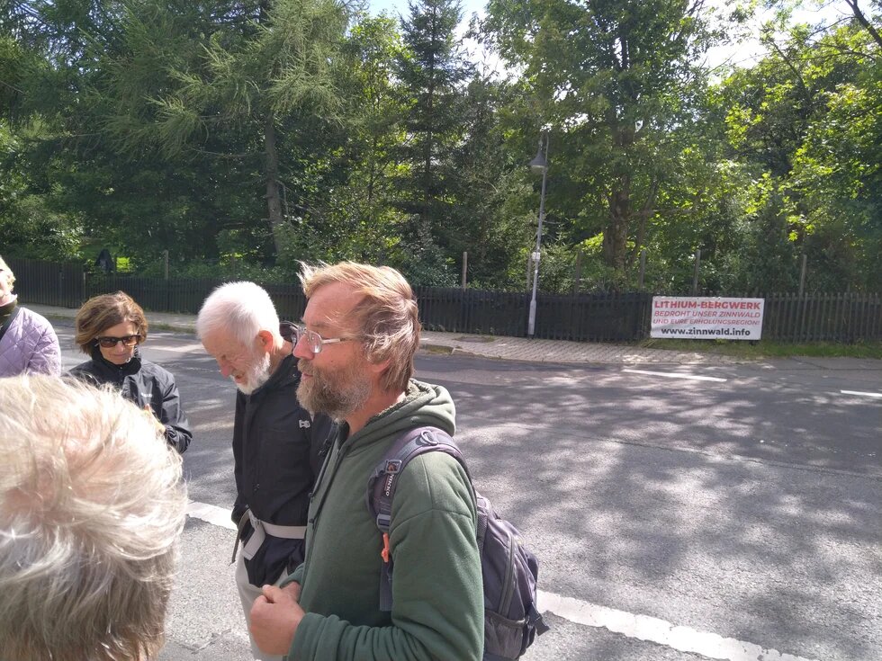 Gesräch über Auswirkungen des Lithium-Abbaus. Im Hintergrund ein Protestschild gegen den Abbau.