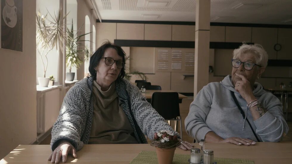 Am Tisch im Speisesaal an einem Vierertisch. Beide Frauen sitzen nebeneinander und sind im Gespräch.