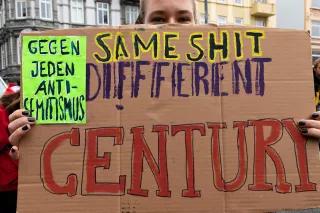 Eine Frau trägt in selbstgebasteltest Schild mit der Aufschrift: Same Shit, Different Century – gegen jeden Antisemitismus
